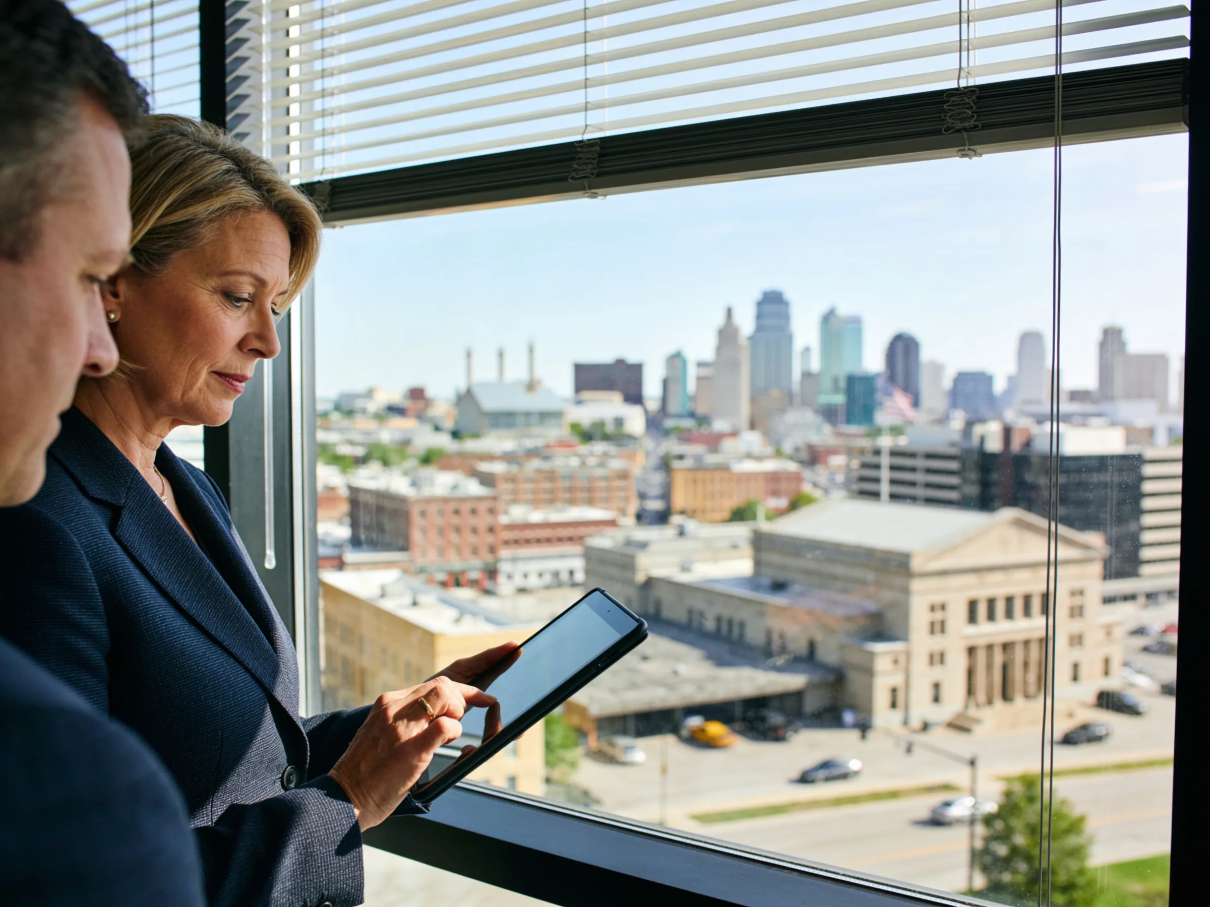 A finance executive reviewing figures with a colleague near an office window